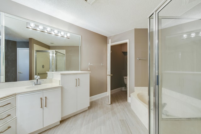 full bathroom featuring vanity, hardwood / wood-style flooring, separate shower and tub, toilet, and a textured ceiling