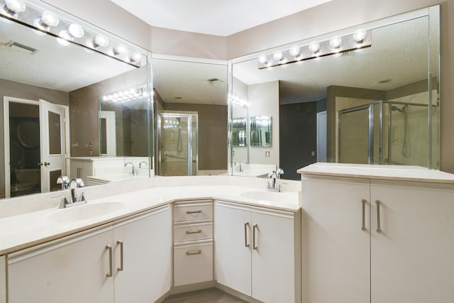 bathroom with a textured ceiling, vanity, and walk in shower