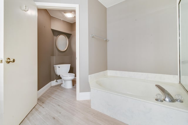 bathroom featuring a bathing tub, toilet, a textured ceiling, and hardwood / wood-style flooring