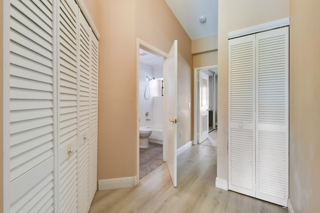 hall featuring light wood-type flooring and a textured ceiling