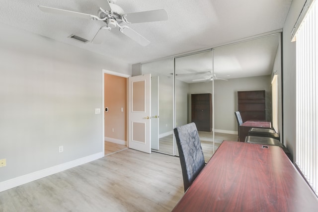 unfurnished office with a textured ceiling, light hardwood / wood-style flooring, and ceiling fan