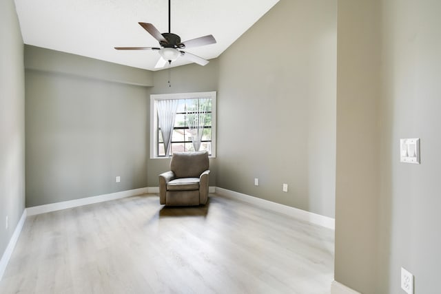 sitting room with ceiling fan, vaulted ceiling, and light wood-type flooring