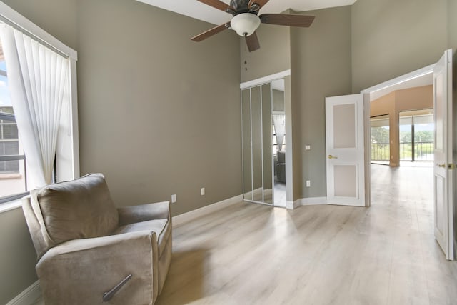 sitting room featuring a wealth of natural light, ceiling fan, a high ceiling, and light wood-type flooring