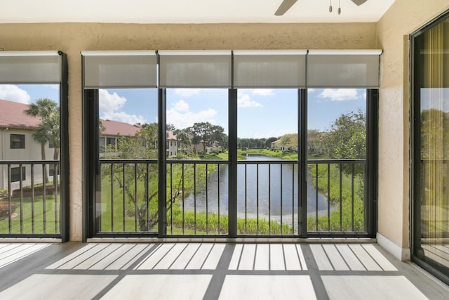 unfurnished sunroom with ceiling fan and a water view