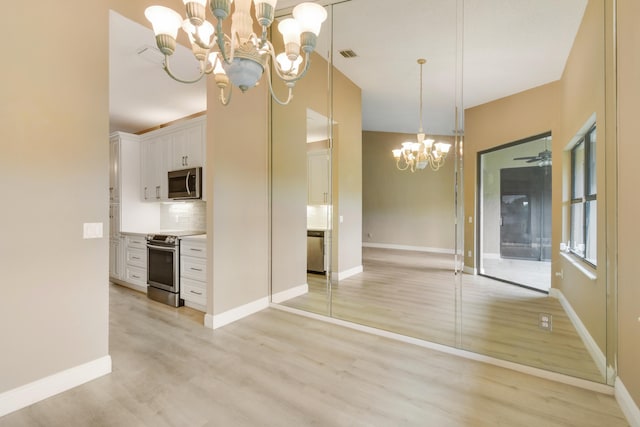 kitchen with hanging light fixtures, light hardwood / wood-style flooring, backsplash, white cabinets, and appliances with stainless steel finishes