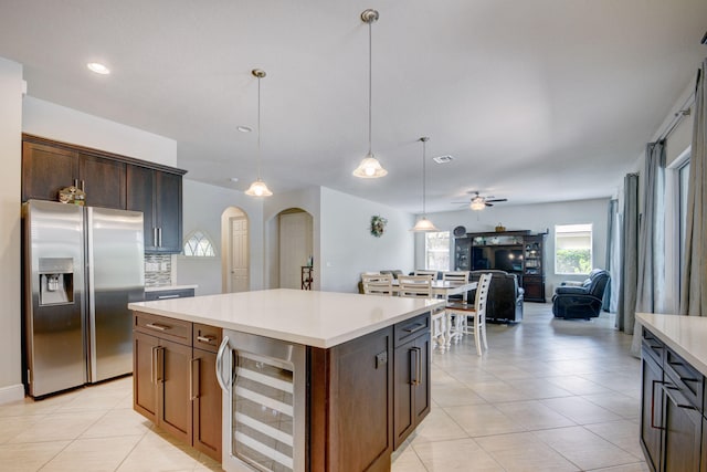 kitchen with stainless steel fridge, wine cooler, dark brown cabinets, a center island, and ceiling fan