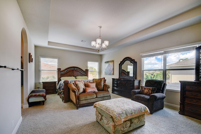 carpeted bedroom featuring an inviting chandelier and a raised ceiling