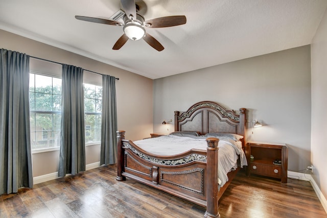 bedroom with a textured ceiling, dark wood-type flooring, and ceiling fan