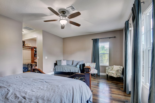 bedroom featuring a closet, a textured ceiling, dark wood-type flooring, a spacious closet, and ceiling fan