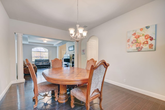 dining area featuring ornate columns, an inviting chandelier, and dark wood-type flooring