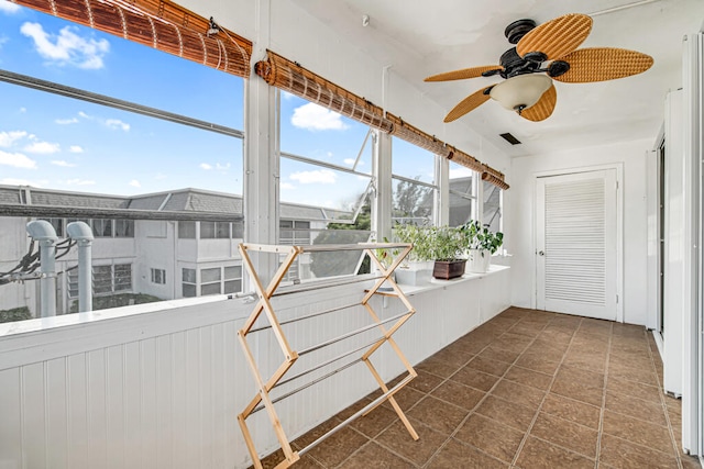 unfurnished sunroom featuring ceiling fan