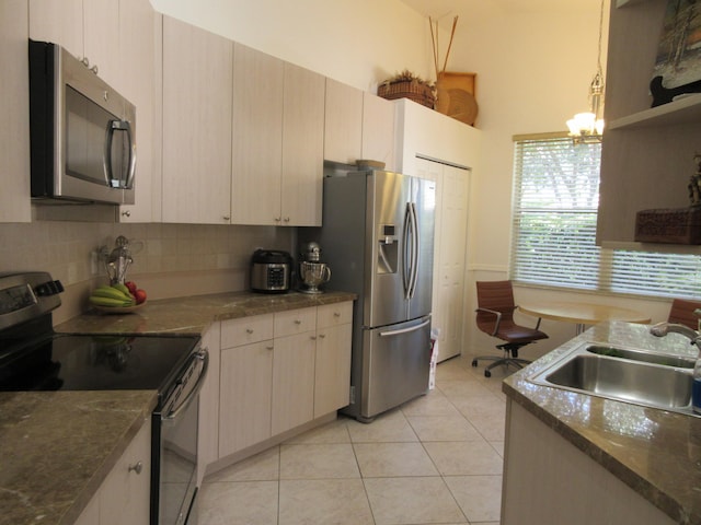 kitchen featuring light tile patterned floors, backsplash, appliances with stainless steel finishes, decorative light fixtures, and sink