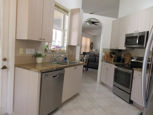 kitchen with light tile patterned flooring, ceiling fan, sink, appliances with stainless steel finishes, and backsplash