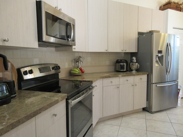 kitchen featuring light tile patterned floors, backsplash, and stainless steel appliances