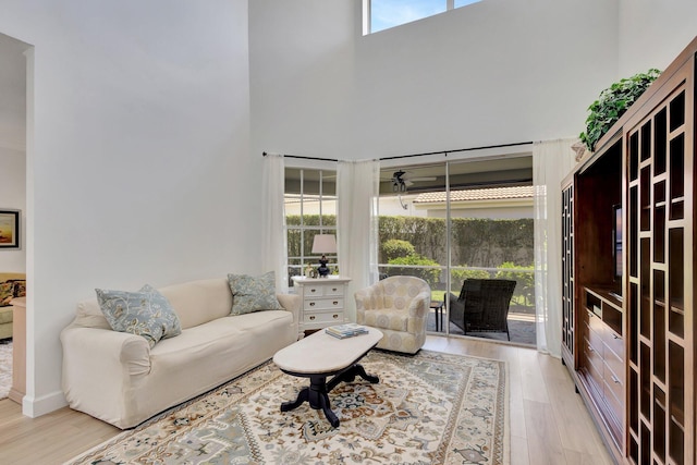 living room with a wealth of natural light, a high ceiling, and light wood-type flooring