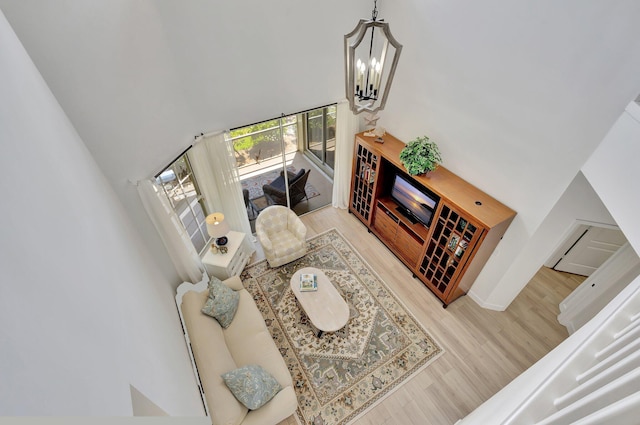 living room with an inviting chandelier, wood-type flooring, and a towering ceiling