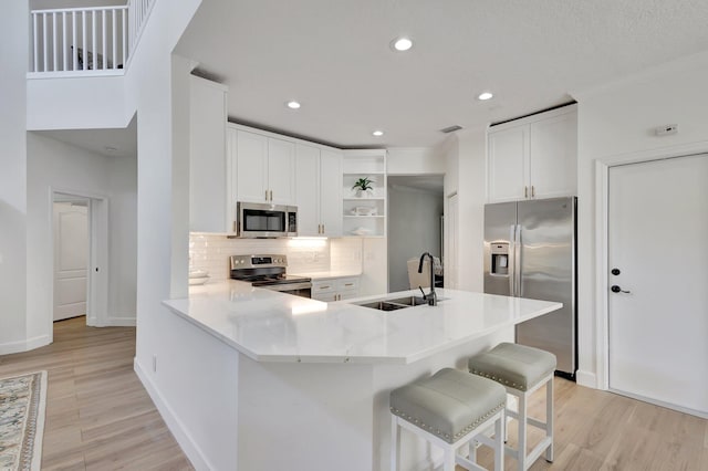 kitchen featuring backsplash, stainless steel appliances, sink, and light wood-type flooring