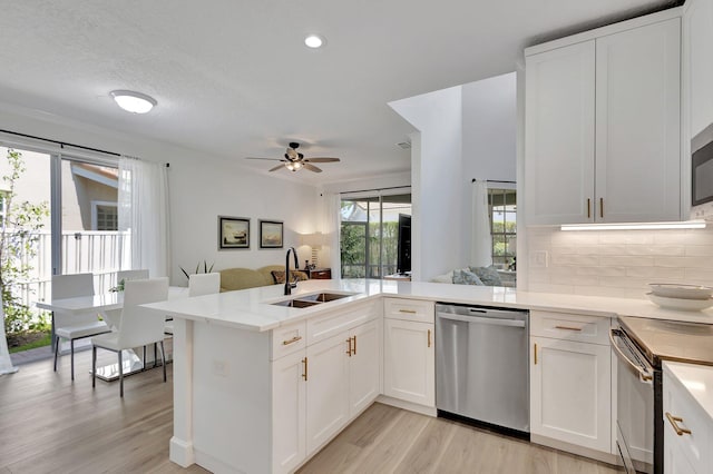 kitchen with ceiling fan, sink, stainless steel appliances, light hardwood / wood-style flooring, and kitchen peninsula