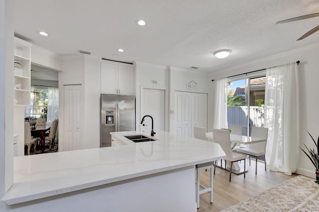 kitchen featuring light hardwood / wood-style flooring, ceiling fan, stainless steel refrigerator with ice dispenser, white cabinetry, and sink