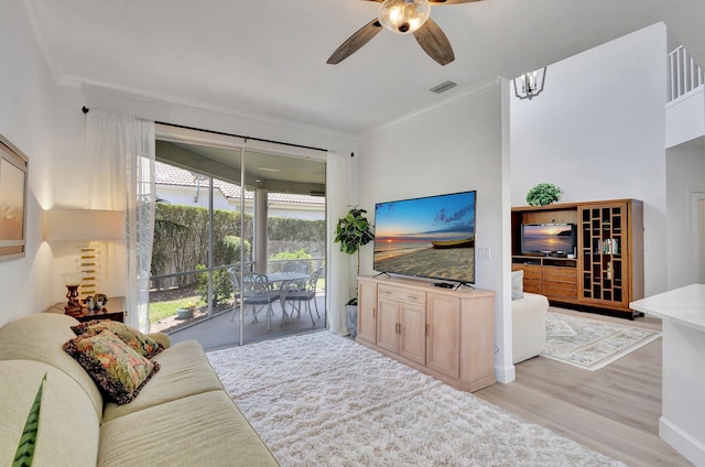 living room with plenty of natural light, crown molding, ceiling fan, and light wood-type flooring