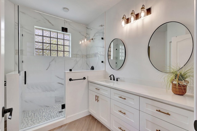 bathroom featuring a shower with shower door and vanity