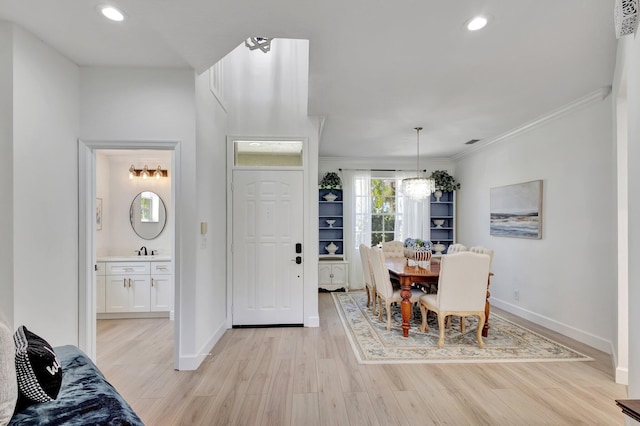 dining area with ornamental molding, a chandelier, sink, and light wood-type flooring