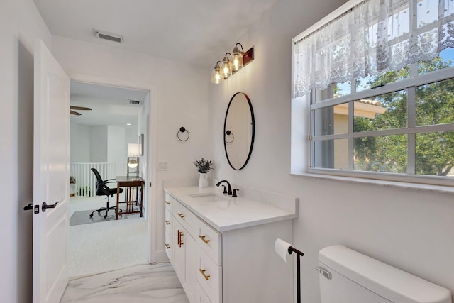 bathroom featuring ceiling fan, vanity, toilet, and a wealth of natural light