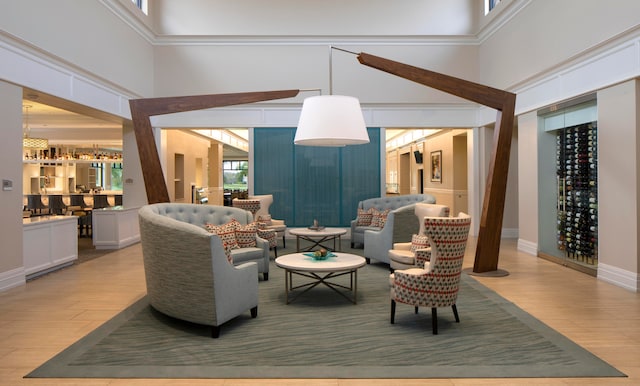 living room with ornamental molding, a towering ceiling, and light wood-type flooring