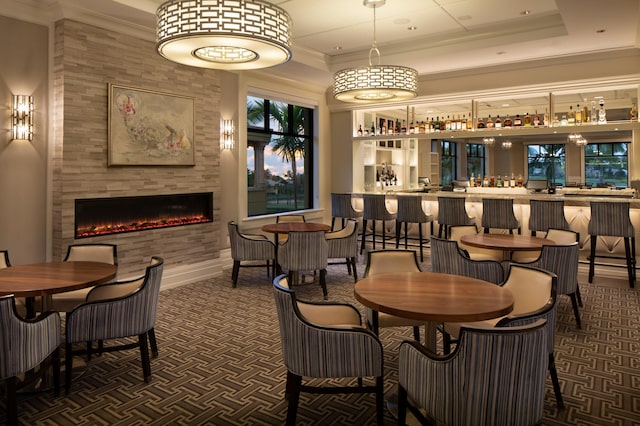 dining area featuring a tray ceiling, a fireplace, and crown molding