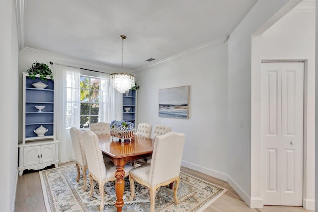 dining space featuring a notable chandelier, light hardwood / wood-style flooring, and crown molding