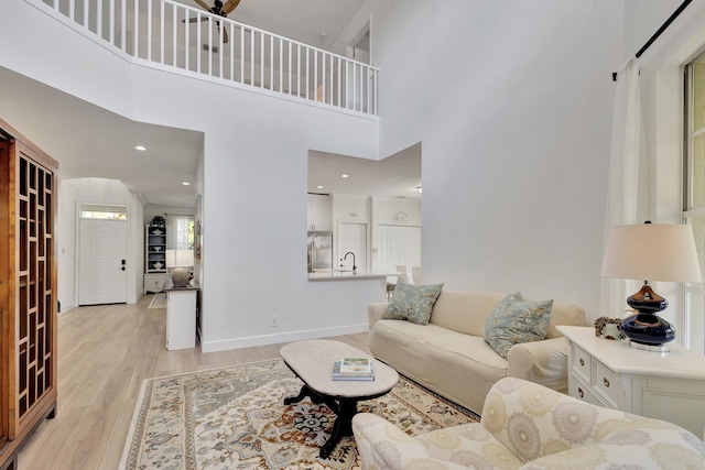 living room with sink, light hardwood / wood-style flooring, and a high ceiling