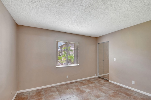 empty room with a textured ceiling and light tile floors