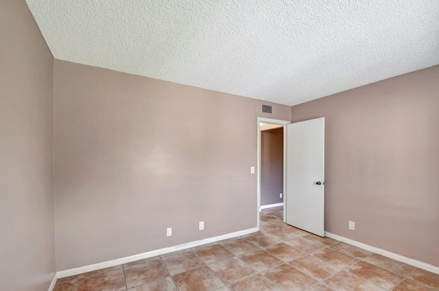 empty room with a textured ceiling and light tile floors