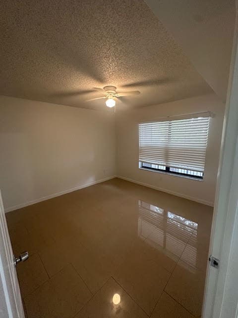 tiled empty room with a textured ceiling and ceiling fan