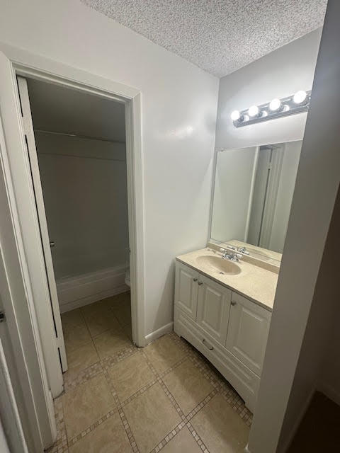 bathroom with a textured ceiling, oversized vanity, and tile flooring