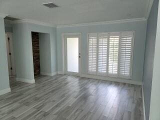 empty room with hardwood / wood-style floors and ornamental molding