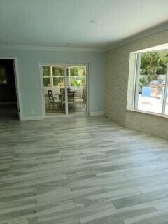 unfurnished room featuring hardwood / wood-style flooring, a healthy amount of sunlight, and crown molding