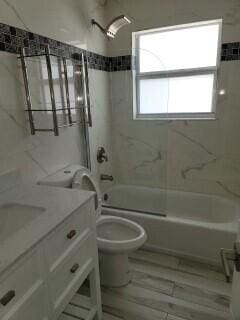 full bathroom with vanity, tiled shower / bath combo, toilet, and hardwood / wood-style flooring