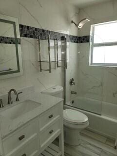 full bathroom with tiled shower / bath, vanity, and toilet