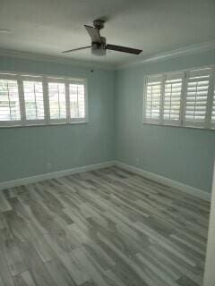 unfurnished room with wood-type flooring, ceiling fan, a healthy amount of sunlight, and crown molding