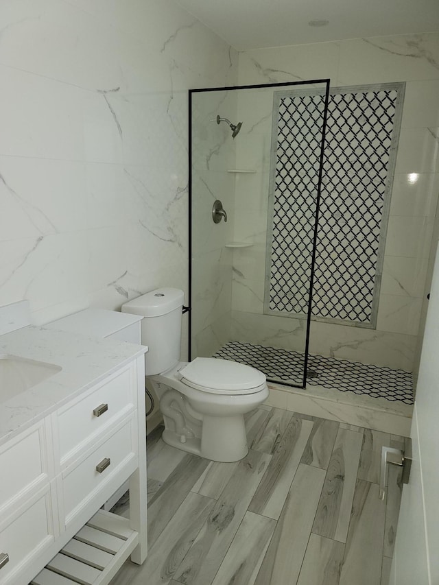 bathroom with tiled shower, wood-type flooring, vanity, and toilet