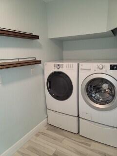 clothes washing area with light hardwood / wood-style flooring and washing machine and dryer