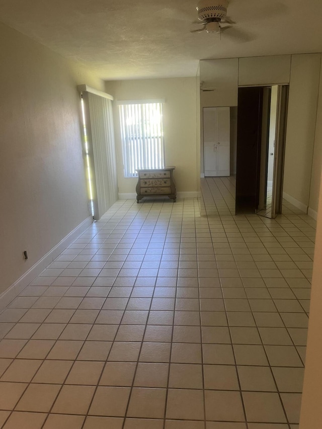 spare room with ceiling fan and light tile patterned flooring