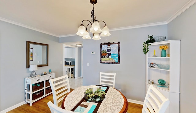 dining space with ornamental molding, light hardwood / wood-style floors, and an inviting chandelier