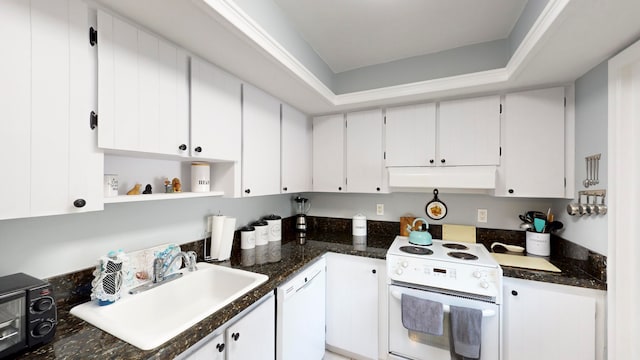 kitchen with white cabinetry, white appliances, dark stone counters, sink, and a raised ceiling