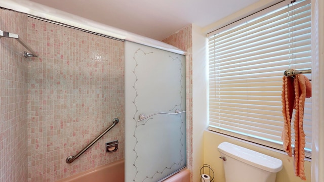 bathroom featuring bath / shower combo with glass door and toilet