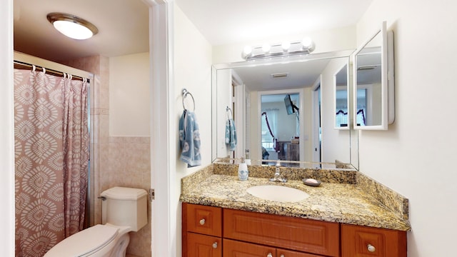 bathroom featuring tile walls, vanity, and toilet