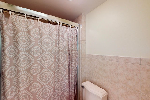 bathroom featuring tile walls and toilet