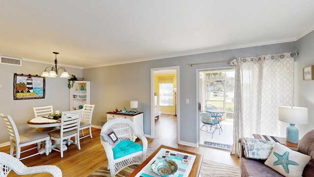 living room with a chandelier, light wood-type flooring, and crown molding