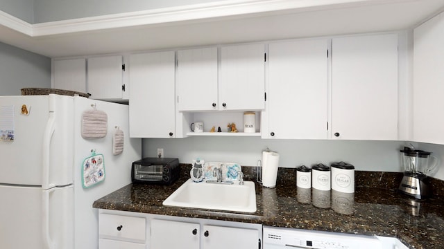 kitchen with white cabinetry, sink, and white fridge